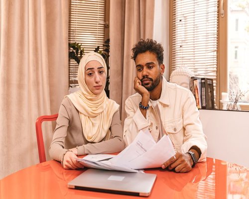 A family sitting at a table reviewing their monthly household budget checklist